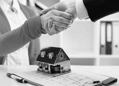 Two people shaking hands above a model of a house