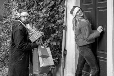 Image of two people entering house with xmas presents